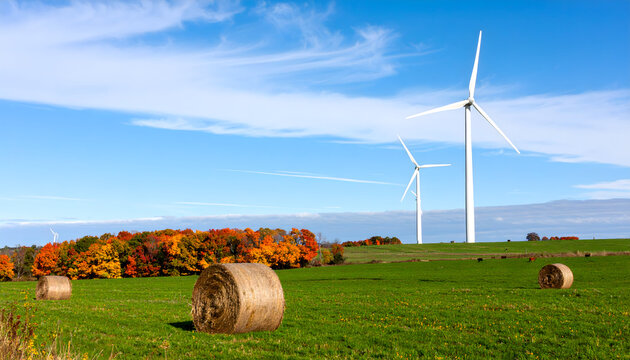 Scenic Autumn Landscape with Wind Turbines and Hay Bales in a Green Field