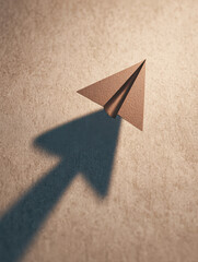 A paper arrow points upward, casting a shadow on a textured surface, evoking themes of direction and creativity in a minimalist style.