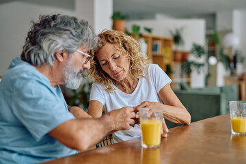 Worried senior couple calculating home finance and domestic bills while having breakfast at table...