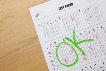 Answer sheet with word Ok on wooden table, top view. Student passing exam