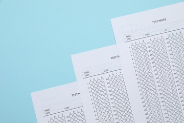 Answer sheets on light blue background, flat lay. Student passing exam