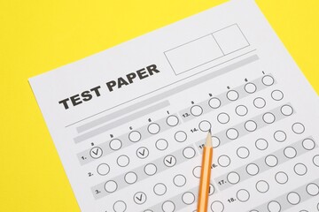 Answer sheet and pencil on yellow background, closeup. Student passing exam