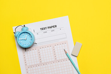 Answer sheet, alarm clock, pencil and eraser on yellow background, flat lay. Student passing exam