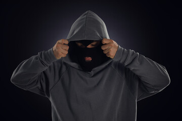 Criminal in mask and hood on dark background