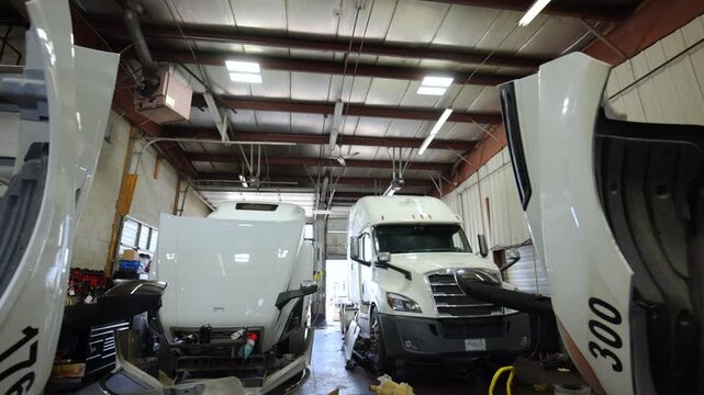 The rows of trucks with open hoods under the repair at the repair shop , Various devices in the repair shop. Semi truck maintenance services. Wide rear view. 