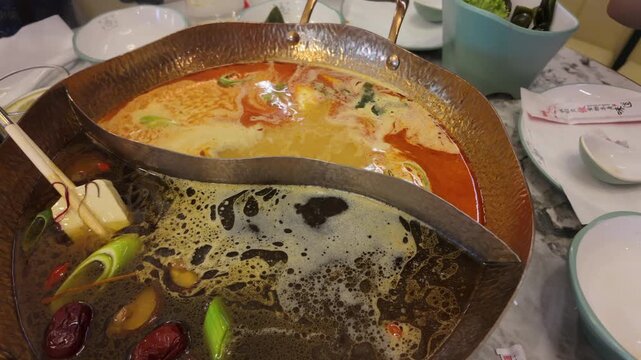 Asian restaurant menu on the tabel featuring hot pot broths, ramen, seafood, meats, vegetables, and tofu.