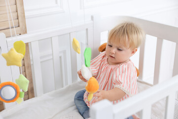 Cute little baby in crib in room