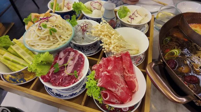 Asian restaurant menu on the tabel featuring hot pot broths, ramen, seafood, meats, vegetables, and tofu.