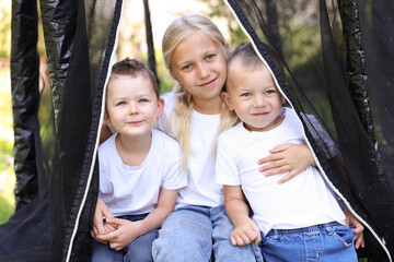 Happy children posing on black trampoline outdoors