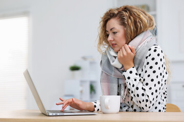 Air conditioning. Woman with scarf suffering from cold temperature at workplace in office