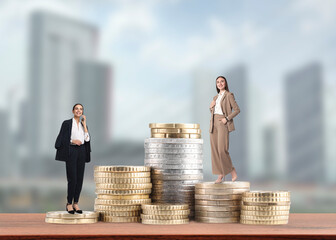 Business women on stacked coins against cityscape. Different income