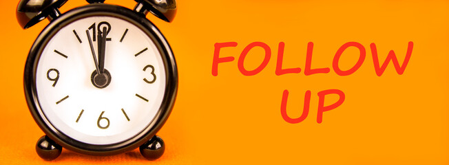 Follow up symbol. Concept word Follow up on beautiful orange paper. Beautiful black alarm clock....