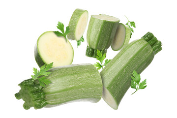 Pieces of fresh zucchinis and parsley falling on white background