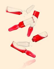 Many ampoules and glass pieces falling on pink beige background