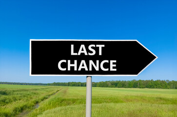Last chance symbol. Concept word Last chance on beautiful black road sign. Beautiful green grass...