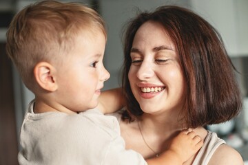 Happy cheerful mother holding her child in arms, enjoying family time and expressing love and joy.