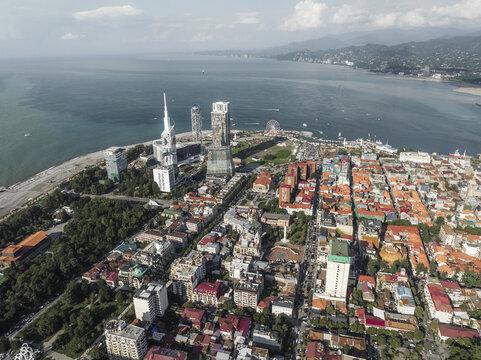 Aerial view of the contrasting red rooftops meeting the Black Sea near the Alphabet Tower and Batumi Ferris Wheel, Batumi, Adjara, Georgia.