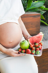 Expectant mother holding a plate with fresh summer fruits