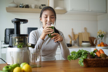 Asian woman enjoying homemade vegetable juice in a home kitchen. Healthy lifestyle and wellness concept