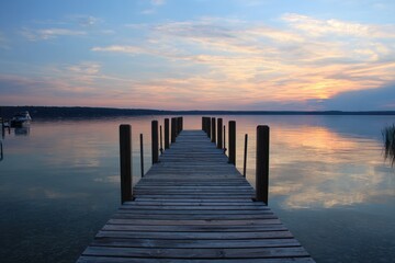 Obraz premium Serene Sunset Over Dock at Torch Lake, Michigan - A Tranquil Vacation Escape