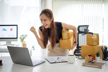 Excited online seller celebrating in front of a laptop after receiving multiple online sales....