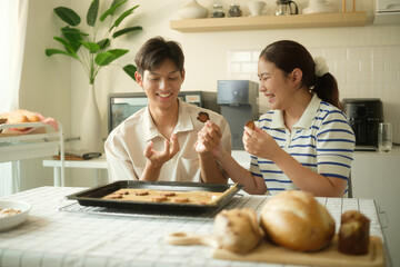 Cheerful couple enjoying their homemade cookies fresh out of the oven in a cozy kitchen.