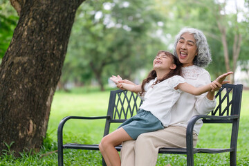 Grandmother and granddaughter laugh heartily while stretching out their arms in joy.
