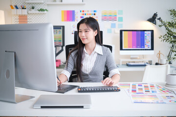 Creative woman using a pen tablet while working on graphic design at her desk.