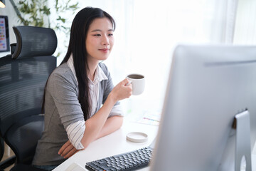 Designer focused on screen with coffee mug and color charts on desk.