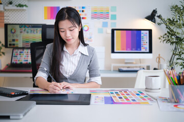 Woman designing with color swatches and drawing tablet in creative office.
