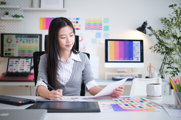 Female designer analyzes color palettes while working at a creative desk.