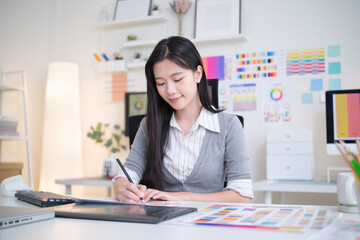 Designer sketches color samples on paper in a bright, organized office.