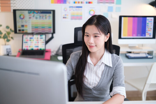 Young female designer focused on computer screen in modern creative office.
