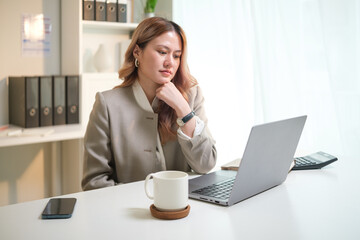 Focused businesswoman working with laptop in bright office.