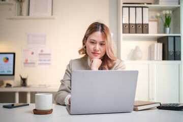 Focused businesswoman working with laptop in bright office.
