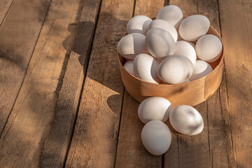Chicken eggs in wooden bowl on grunge table in chicken coop, barn. Countryside outdoor setting in the backyard © TSViPhoto