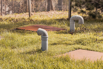 Septic tank system with ventilation pipes and metal covers on a grassy field