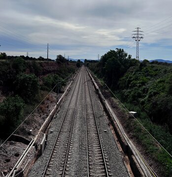 Two pairs of parallel train tracks, photo taken on a bridge, the sky in the background of the tracks