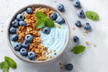 Vibrant blue yogurt parfait bowl with blueberries, granola, and mint