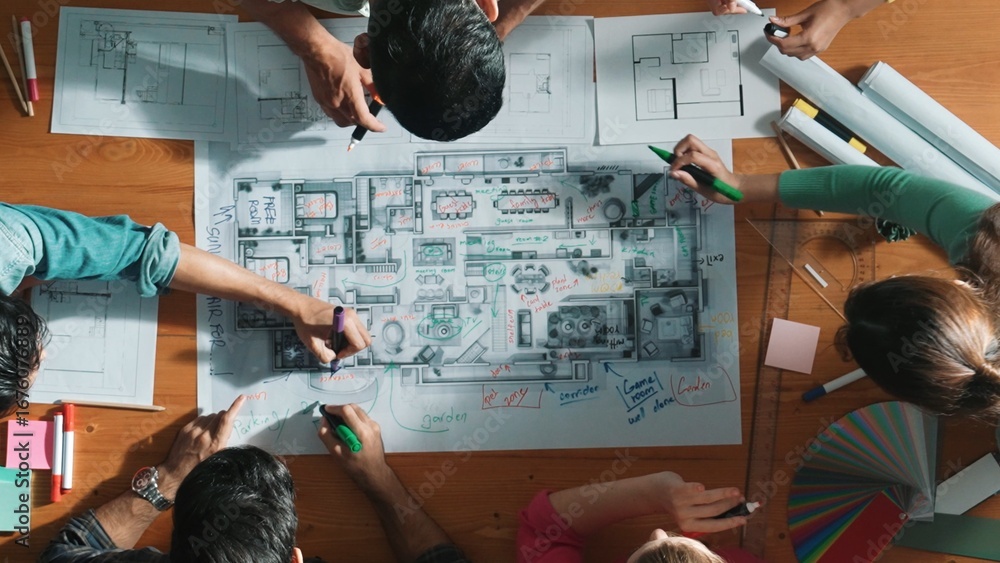 Poster top down view of civil engineer team writing at blueprint at meeting table with color palettes. grou