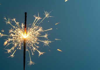 Obraz premium Sparkler burning brightly against a dark blue background with copy space area