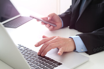 Businessman using laptop and smartphone at office desk