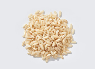 Brown jasmine rice uncooked grains scattered on white background, close up top view.