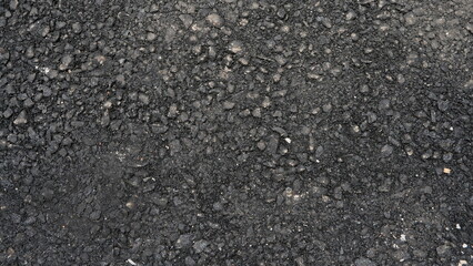 New asphalt pavement texture. A frame filled with the textured surface of dry asphalt, showcasing the detailed pattern. Black asphalt background.