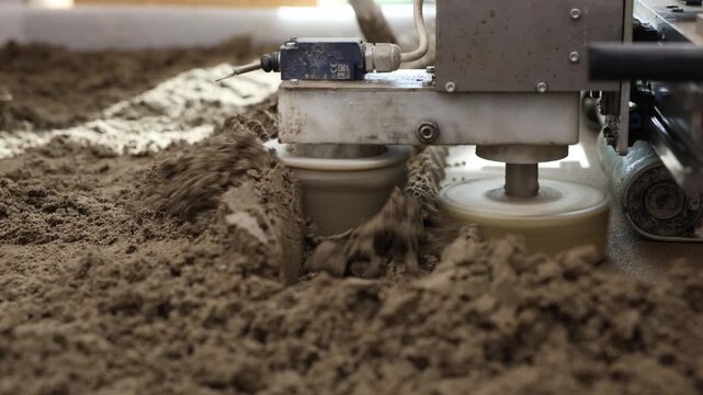 Close up of liquid foam concrete and cement screed being applied and leveled. A machine and tool in motion ensure an even, smooth surface.
