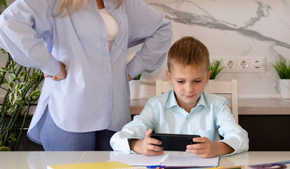 Schoolboy enjoys video games instead of doing homework, while mother takes away child's smartphone,...