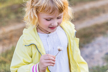 Young child enjoying a sunny day while playing with a flower in a grassy field during late afternoon