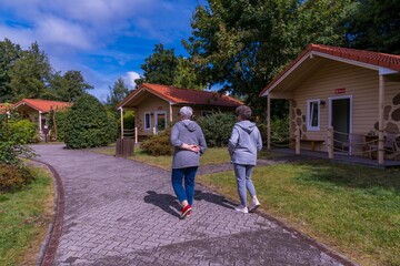 Elderly people walking in front of safari park bungalows. Hodenhagen, Germany 08.17.2025
