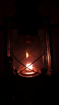 Beautifully glowing antique kerosene lantern hangs against a black background, radiating warmth and vintage charm as it spins gently , evoking a magical festive atmosphere in vertical footage.