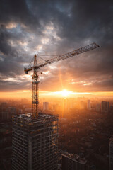 Crane silhouetted against vibrant sunset, construction of the skyscraper, cityscape in golden light.